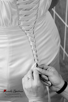 Bridesmaid ties back of wedding dress