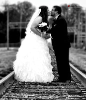 bride and groom kiss on railroad tracks