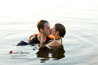 Engaged couple swims in lake and kisses