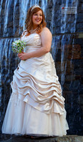 Bride standing on rock in front of water fall.