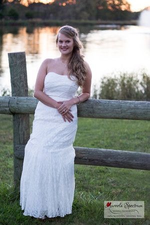 Bride leans on fence in front of lake in Monroe, NC