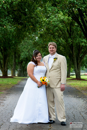 Bride and groom on tree lined drive