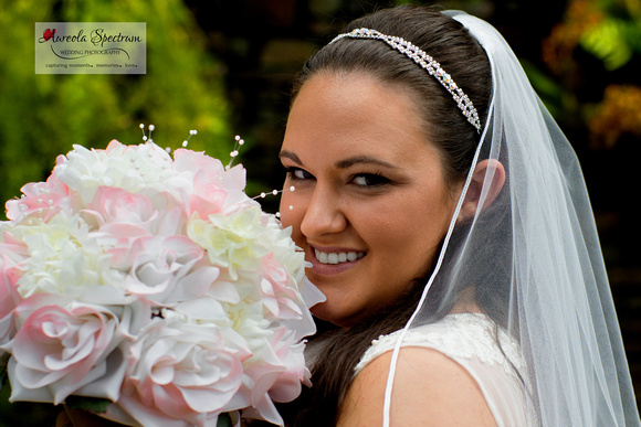 Bride smiles at the camera with her bouquet in hand.