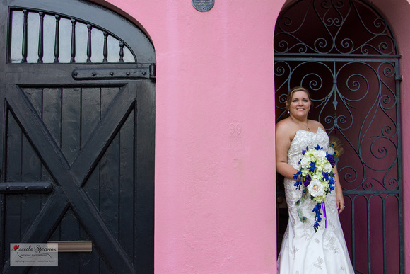 Bride in Rainbow Row in front of pink home.