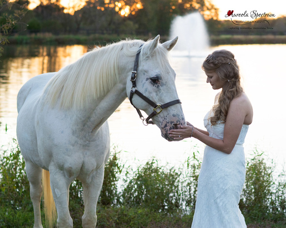 Bride standing with horse in front of pond