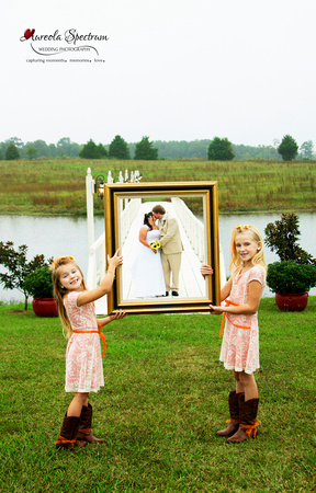 Flower girls hold frame around bride and groom