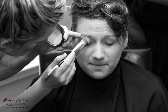 Black and white photo of bride getting her makeup.