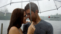 Engaged couple under clear umbrella in the rain.