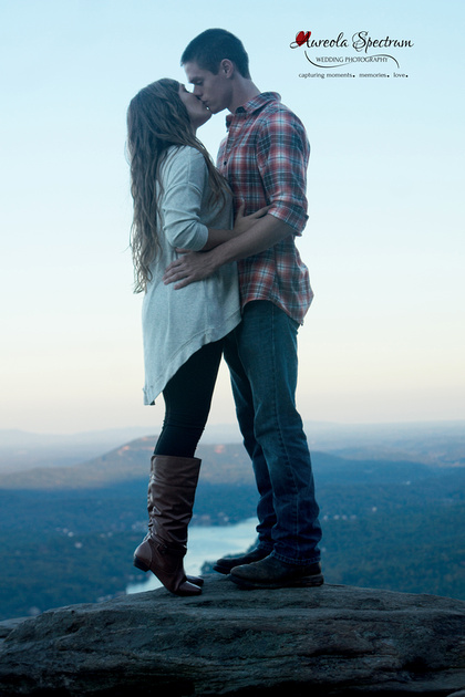 Girl stands on her tippy toes and kisses future husband at a mountain overlook