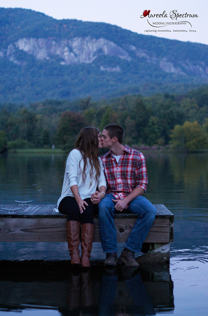 Couple sits on dock and kisses in Lake Lure, NC