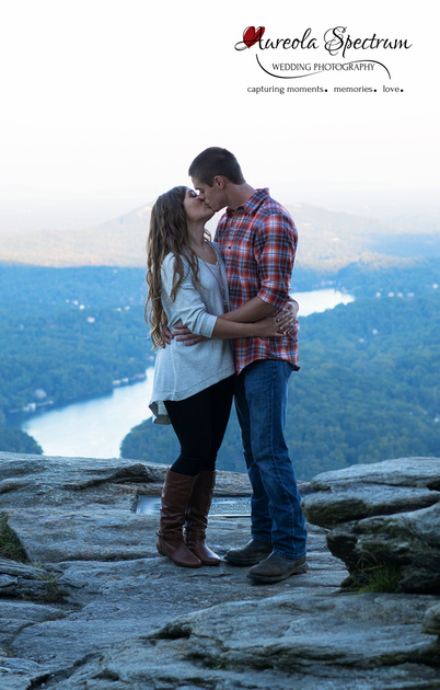 Engaged couple kiss at Chimney Rock overlook