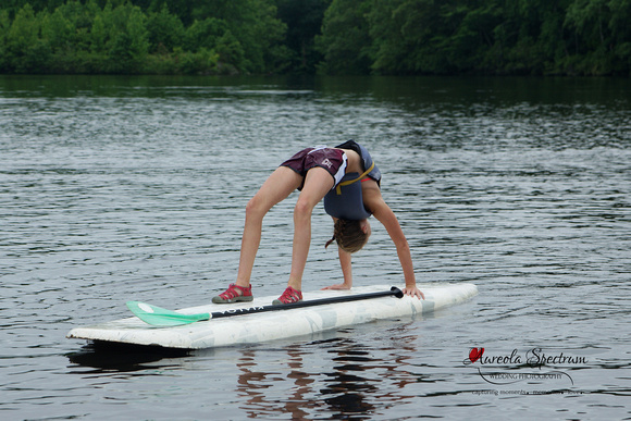 Heart kid does back bend on paddle board at camp luck.