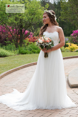 Bride stands near colorful flowers.