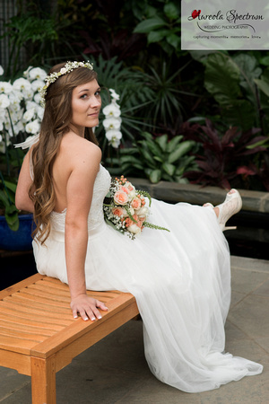 Bride sits on a bench at NC botanical garden.