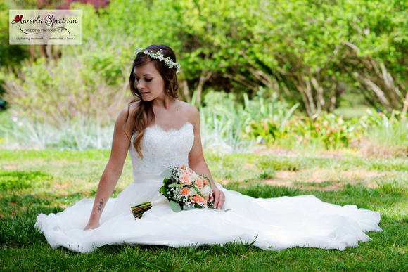 Bride sits in a meadow at Daniel Stowe Botanical Garden.